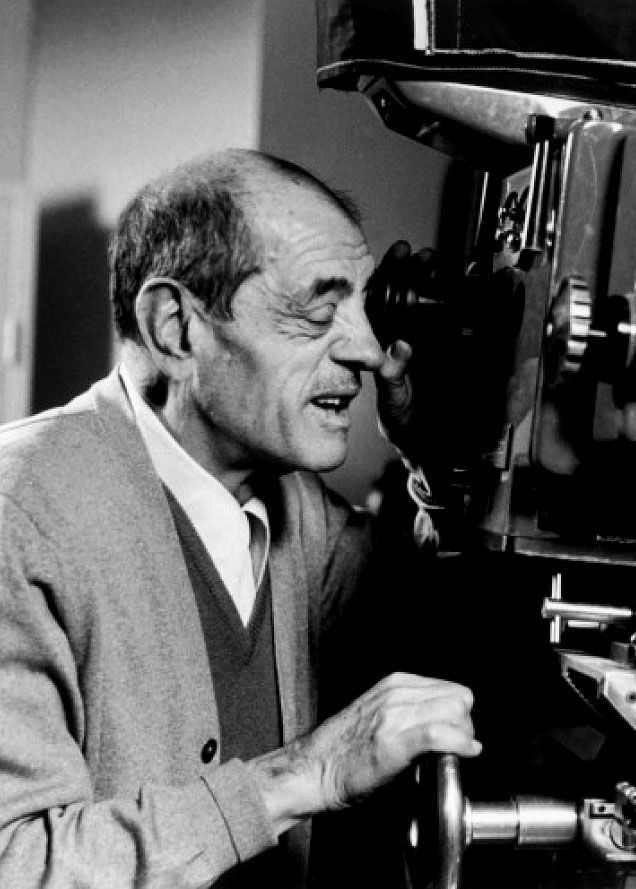 black and white photograph of a man looking through a telescope at something in front of him