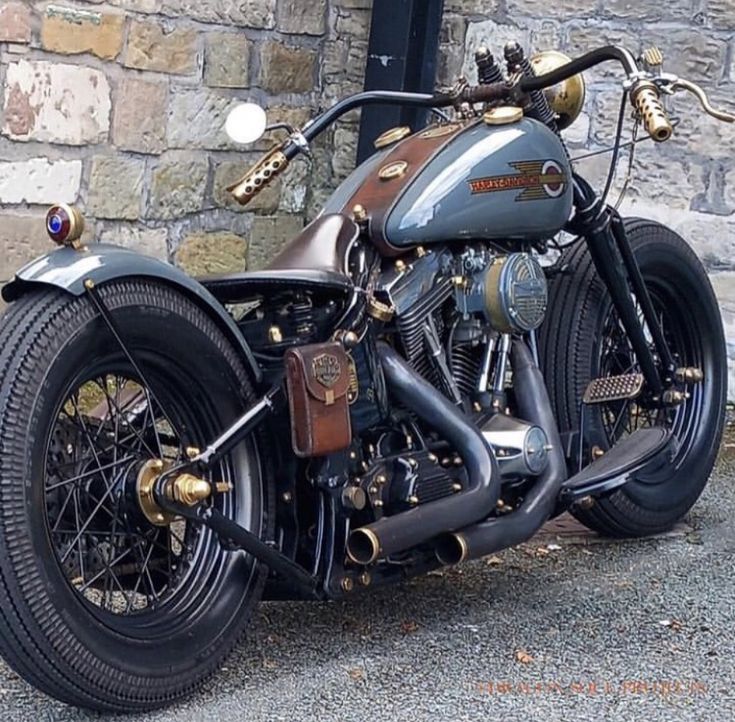 a black motorcycle parked in front of a brick building with gold accents on it's side