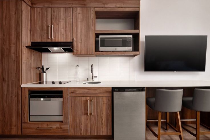 a kitchen with wooden cabinets and stainless steel appliances, including a flat screen tv mounted on the wall