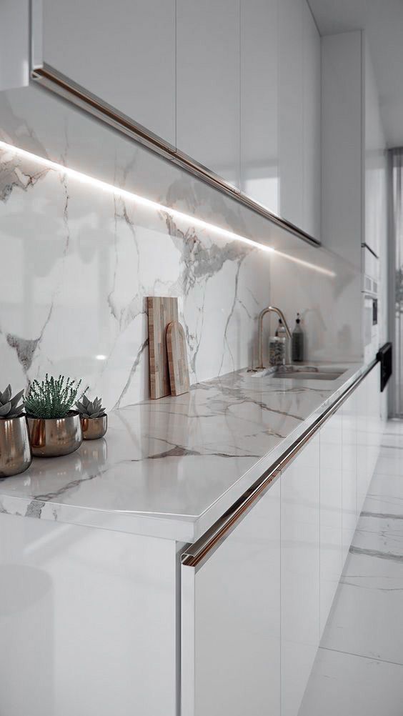 a kitchen counter with green vases and plants on the counter top in front of it