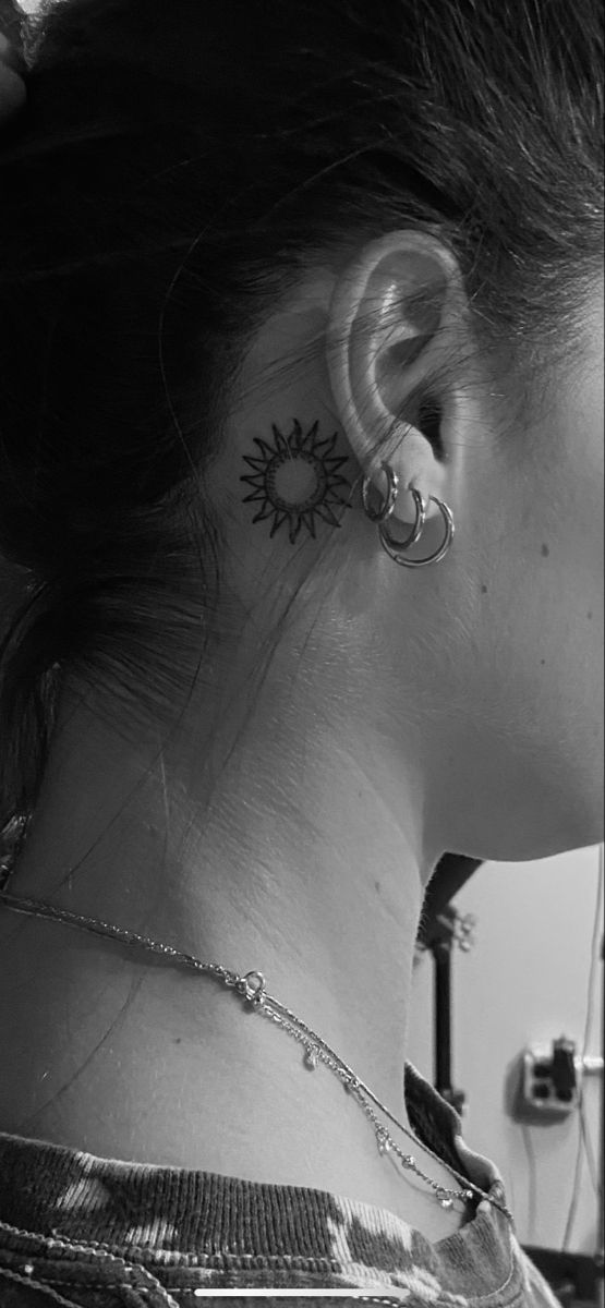 black and white photograph of a woman's ear with sunflower tattoo on it