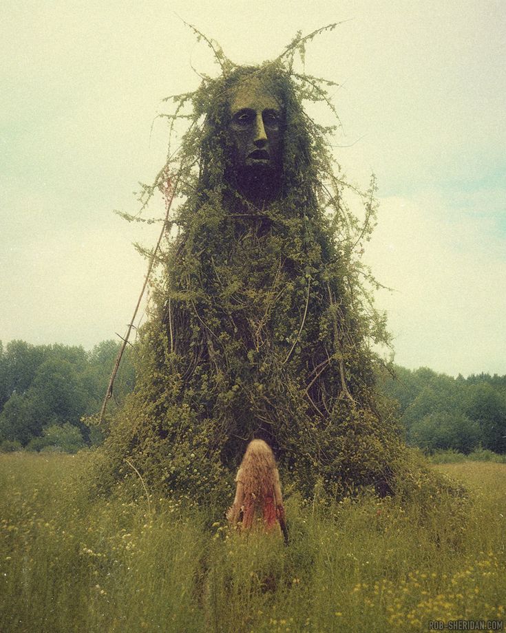 a woman standing in tall grass next to a giant sculpture