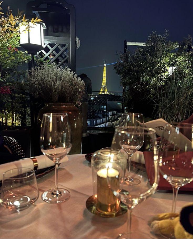 wine glasses on a table with the eiffel tower in the background at night