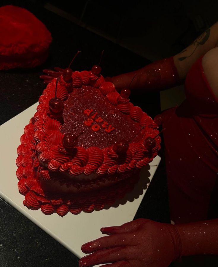 a red heart shaped cake sitting on top of a table