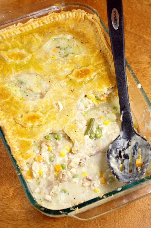 a casserole dish with chicken and vegetables in it next to a serving spoon