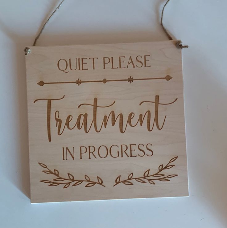 a wooden sign that says quiet please treatment in progress hanging from a string on a wall