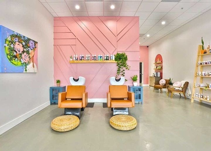 two orange chairs sitting in front of a pink wall with shelves on each side and potted plants behind them