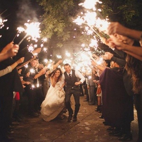 the bride and groom are walking down the path with sparklers in their hands as they exit the wedding ceremony