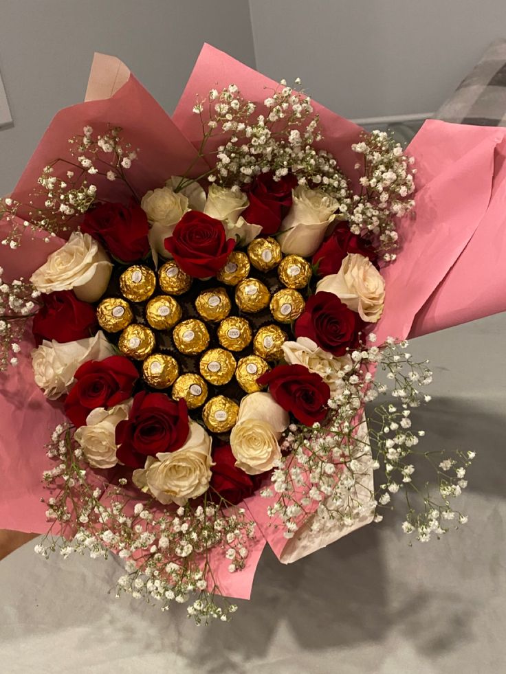 a bouquet of flowers with chocolates and baby's breath