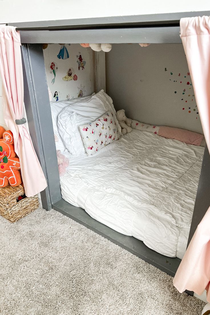 a child's bed with pink curtains on the top and bottom, in a room with carpeted flooring