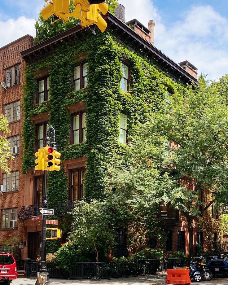 a tall building covered in green ivy next to a traffic light on a city street