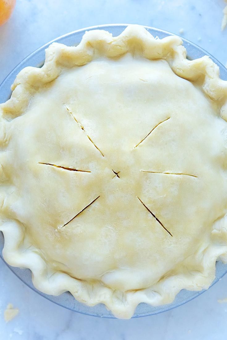 an uncooked pie sitting on top of a blue plate next to oranges