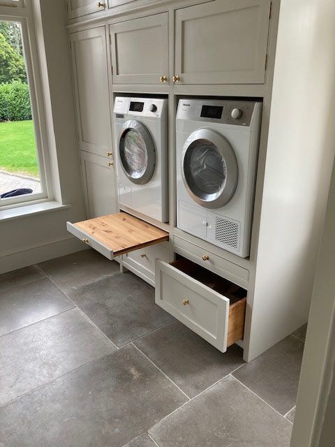 a washer and dryer sitting in a kitchen next to a window with an open drawer