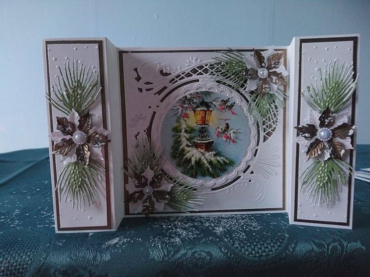 three cards with christmas decorations on them sitting on a blue tablecloth covered surface, one is open and the other two are closed