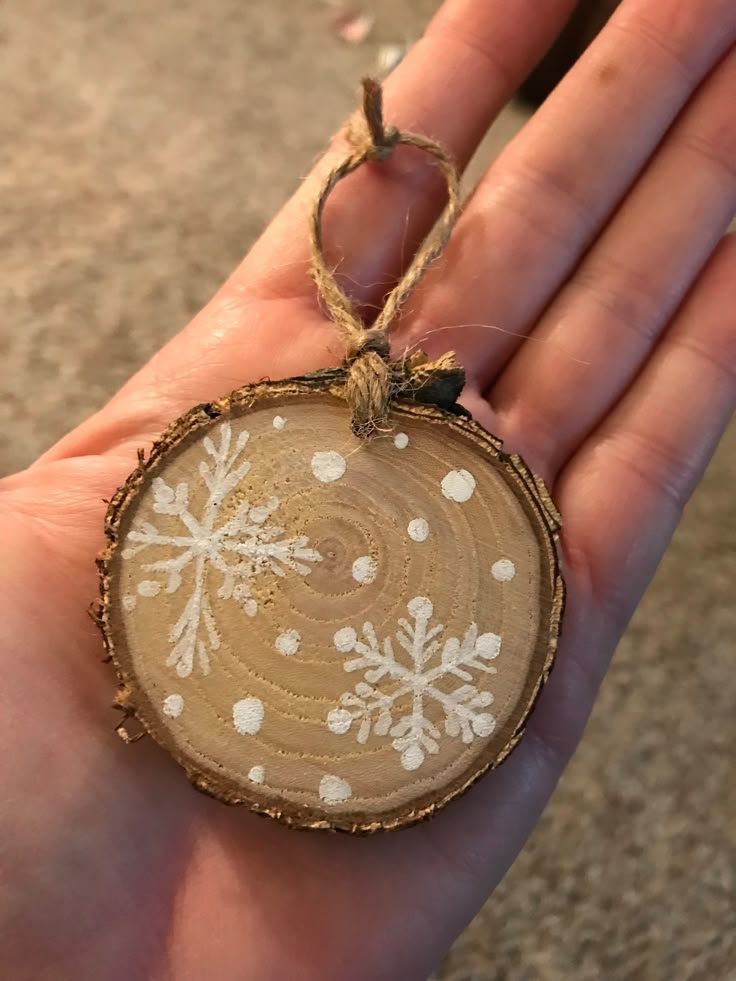 a hand holding a wooden ornament with snowflakes on it's side