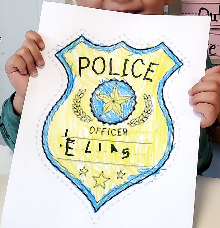 a young boy holding up a drawing of a police badge