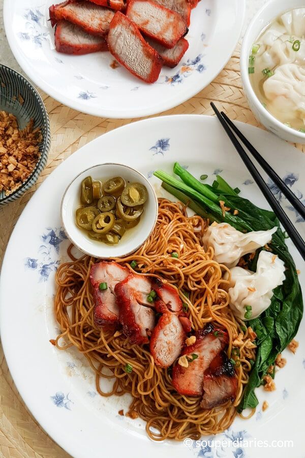 two plates filled with food and chopsticks on top of a wooden table next to bowls