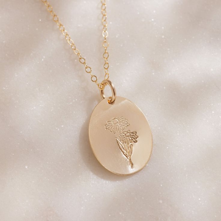 Delicate with a touch of whimsy, this hand-stamped pendant necklace features a flower design that represents your birth month. From the petite snowdrops of January to the classic holly of December, every month is represented (and some with two), making the Birth Month Necklace a great gift for moms, grandparents and friends, or any nature lover in your life. We love the subtle femininity it offers on its own, but because the oval pendant is suspended from a dainty gold chain that falls just belo Charming Flower Charm Necklace Gift, Charming Flower Charm Necklaces For Gift, Anniversary Delicate Flower Charm Necklace, Delicate Charm Necklace With Flower Pendant, Delicate Flower Charm Round Pendant Necklace, Delicate Round Pendant Charm Necklaces With Flower Charm, Delicate Charm Necklace With Round Flower Pendant, Mother's Day Dainty Flower Charm Necklace, Dainty Birth Flower Charm Necklaces