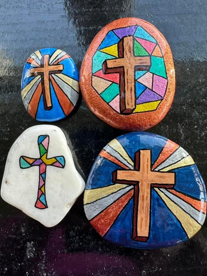 three painted rocks with crosses on them