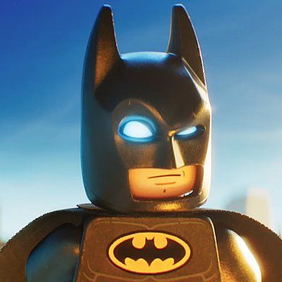 the lego batman movie character has glowing blue eyes and is standing in front of a cityscape