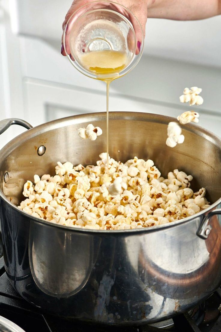 a person pouring something into a pot on top of a stove with some food in it