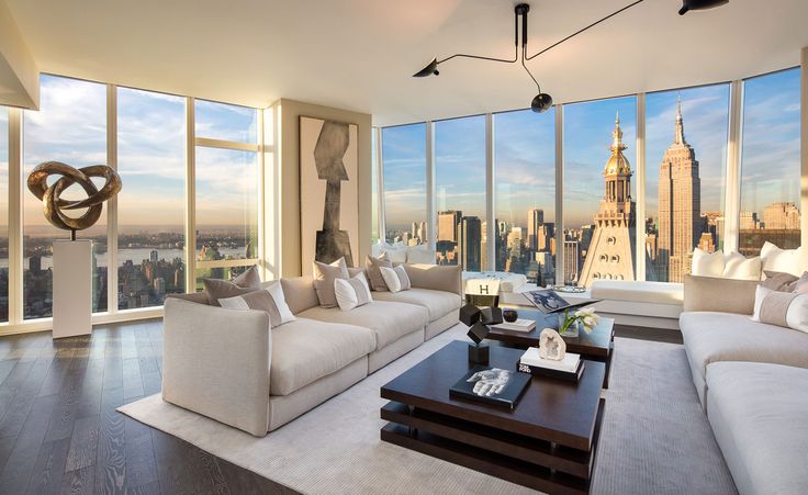 a living room filled with furniture and large windows overlooking the cityscape in the distance