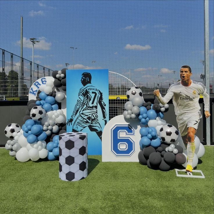 a soccer player is running in front of balloons and decorations on the field with his number six