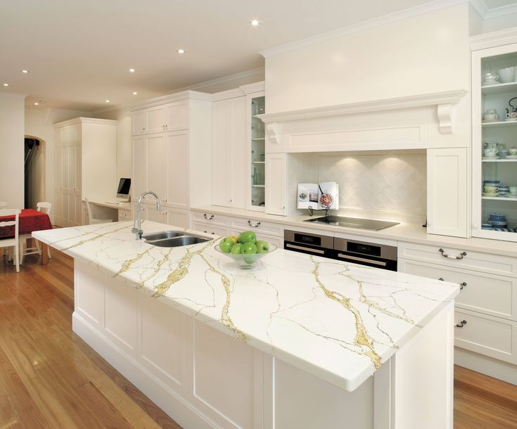 a large kitchen with white cabinets and an island in the middle is shown, along with a red chair