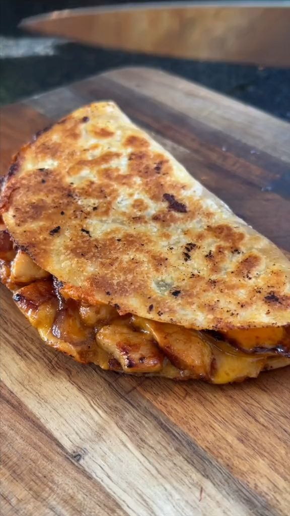 a wooden cutting board topped with a quesadilla