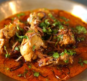 a silver plate topped with meat covered in sauce and garnished with cilantro