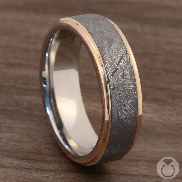 a wedding band with two tone gold and silver inlays, on a wooden surface