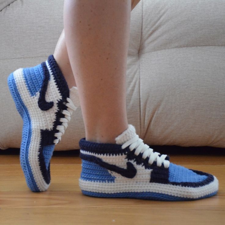 a person wearing blue and white sneakers on top of a wooden floor next to a couch