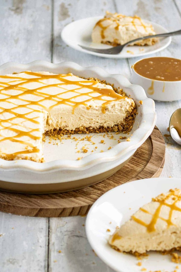 a slice of cheesecake with caramel drizzled on top and two plates next to it