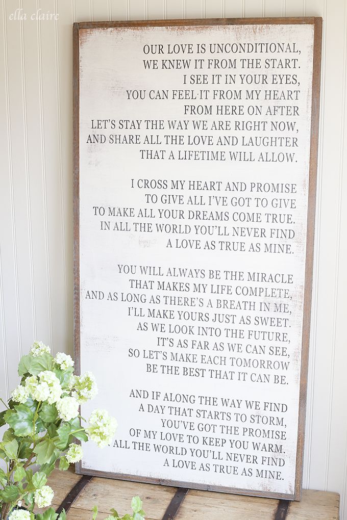 a wooden sign sitting on top of a table next to a vase filled with flowers