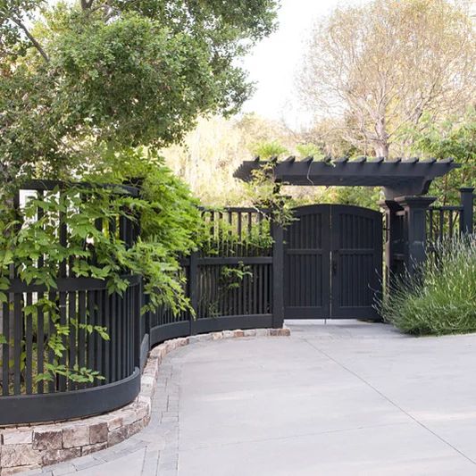 a black gate is surrounded by greenery and trees