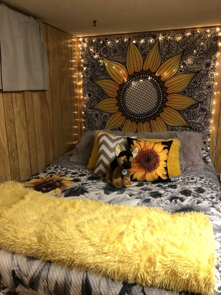 a dog is sitting on the bed in front of a sunflower wall hanging above it