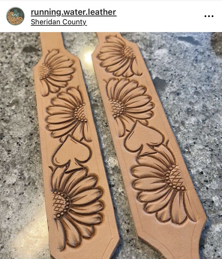 two wooden spoons sitting on top of a counter next to each other with flowers carved into them