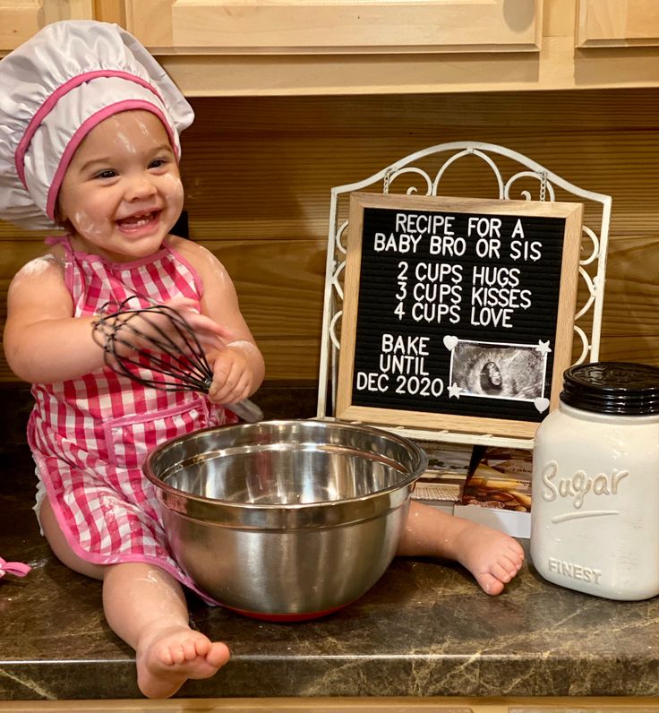 a baby sitting on the kitchen counter holding a whisk and mixing bowl next to a sign that says recipe for a baby