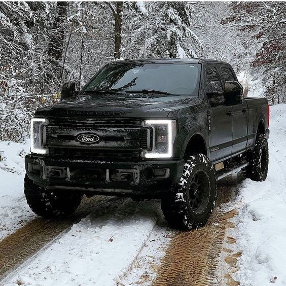 a black truck driving down a snow covered road