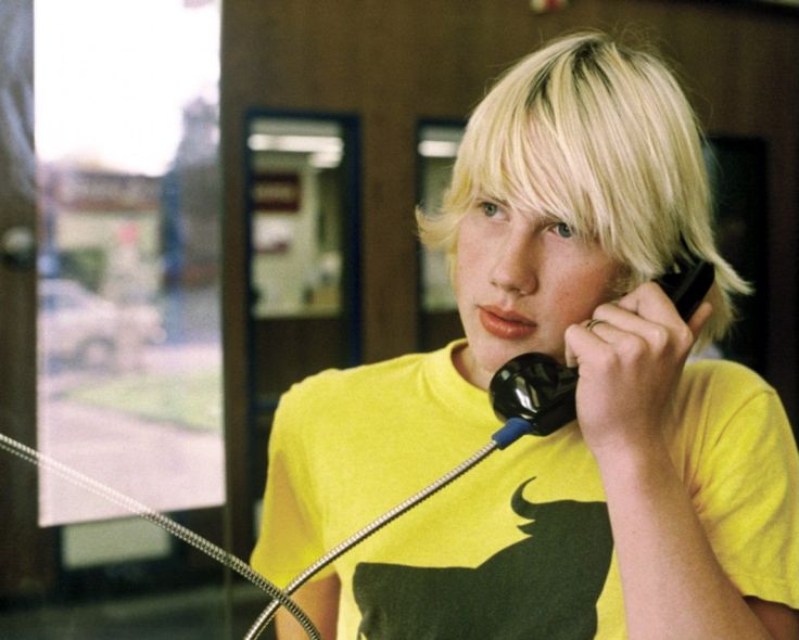 a woman talking on a phone while standing in front of a window