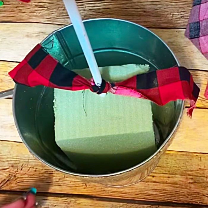 a person holding a red and black bow tie in a metal bowl with green liquid