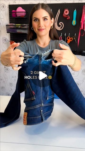 a woman sitting on top of a table holding onto a pair of jeans