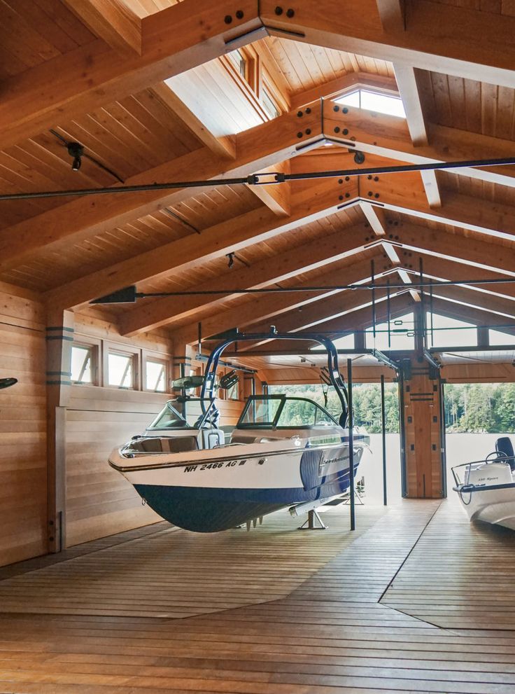 two boats are parked in a boathouse with wooden flooring and beams on the ceiling