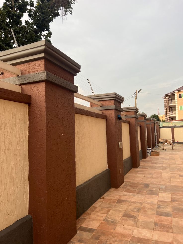 a row of brown pillars on the side of a building next to a brick sidewalk