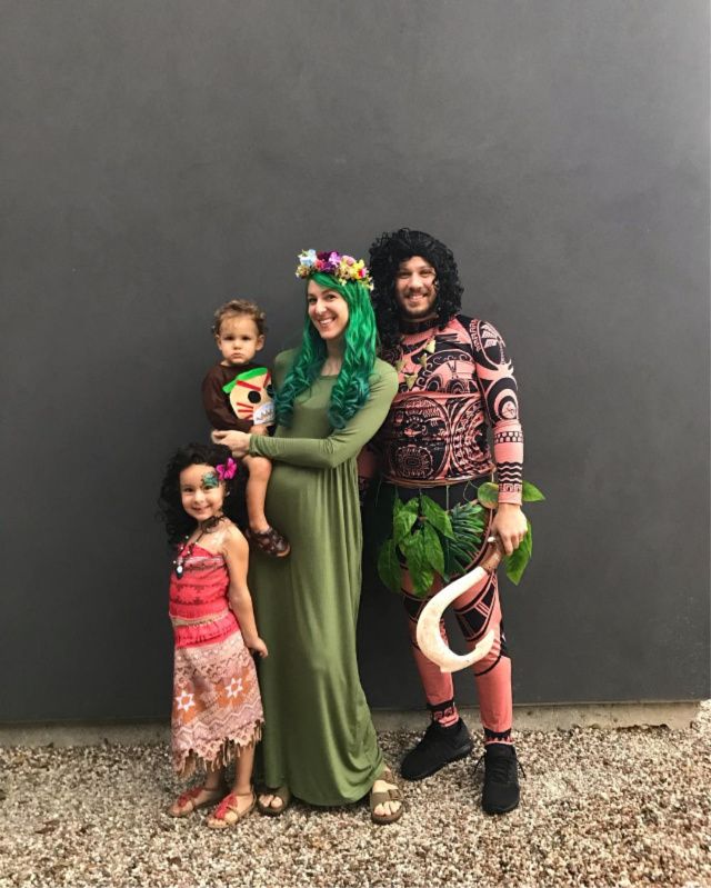 two adults and two children standing in front of a wall with plants on their heads