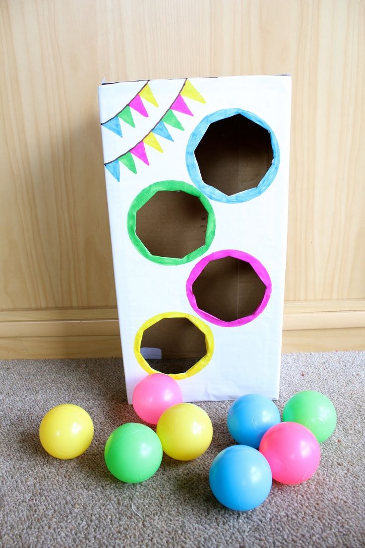 a cardboard box filled with colorful plastic eggs next to some paper mache cutouts