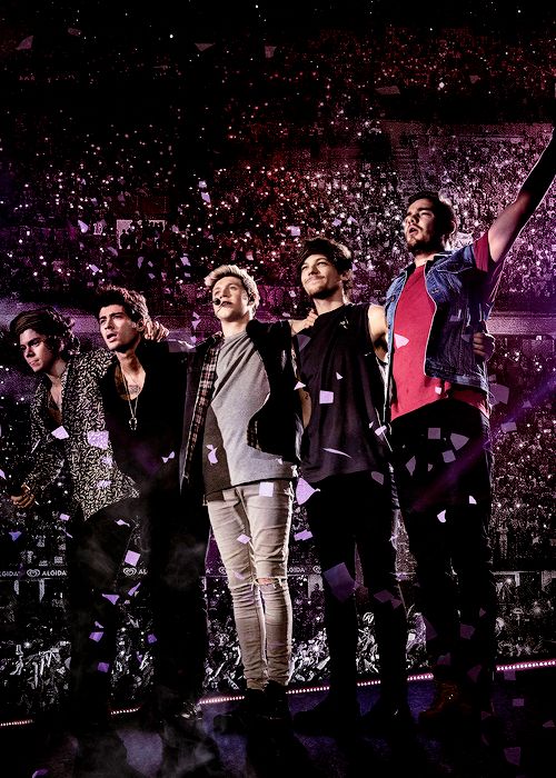 the one direction band standing on stage with their arms in the air and confetti falling around them