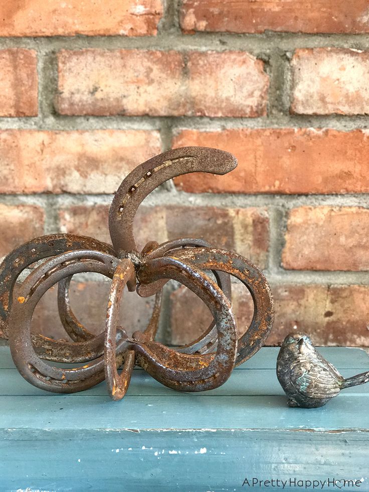 an old metal pumpkin sitting on top of a blue table next to a small bird