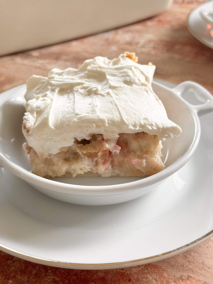 a white plate topped with a piece of cake covered in frosting on top of a table