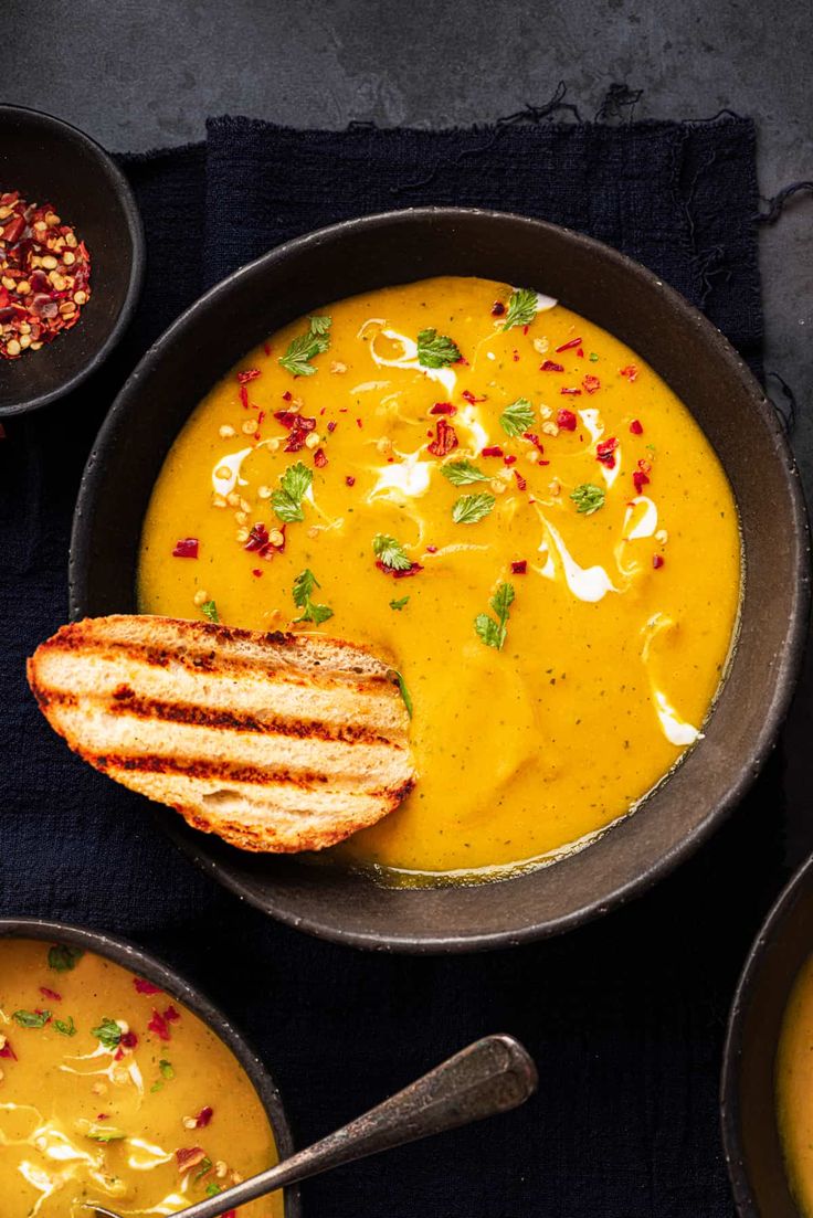 two bowls of soup with grilled bread on the side